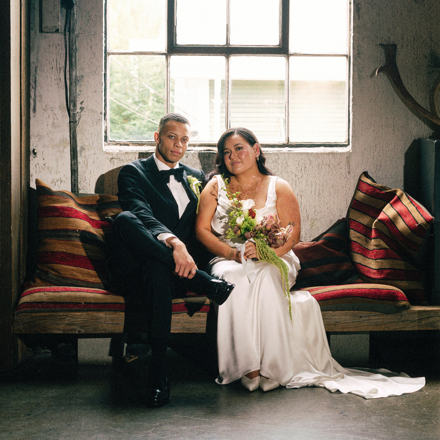 beautiful interracial wedding couple sitting on a sofa inside la fabrique st george winery in vancouver