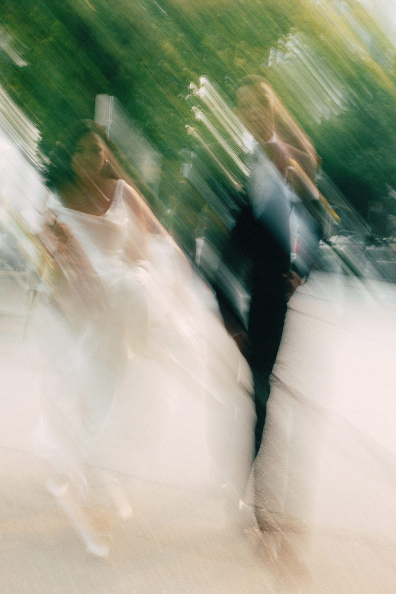 a wedding couple walking down a residential street in vancouver. a motion blur technique is used to signify energy and movement