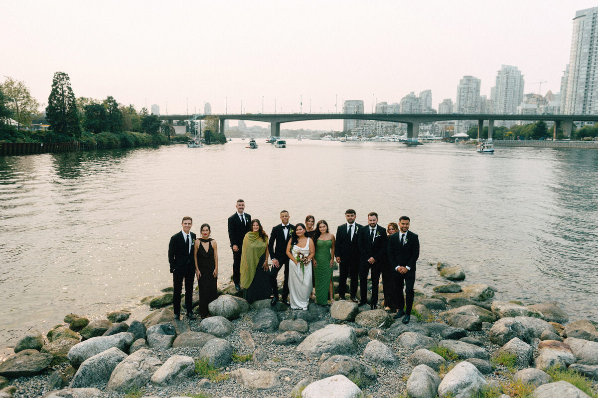 a stylish wedding party posing at habitat island on a smokey summer's day. the vantage point offers a good view of false creek and the cambie street bridge in vancouver
