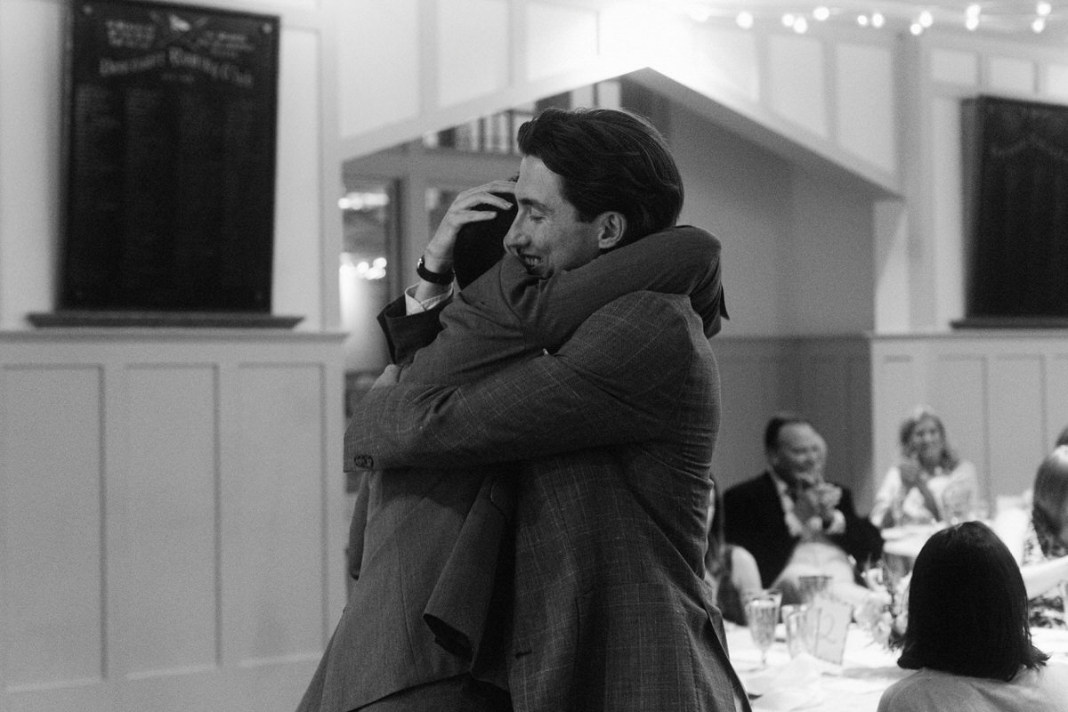 documentary moment of a groom hugging a guest at the Vancouver Rowing Club