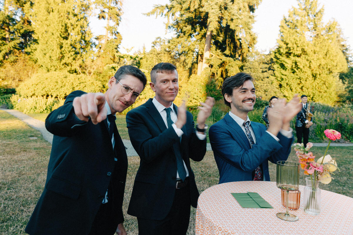 documentary capture of wedding guests playfully pointing at the camera