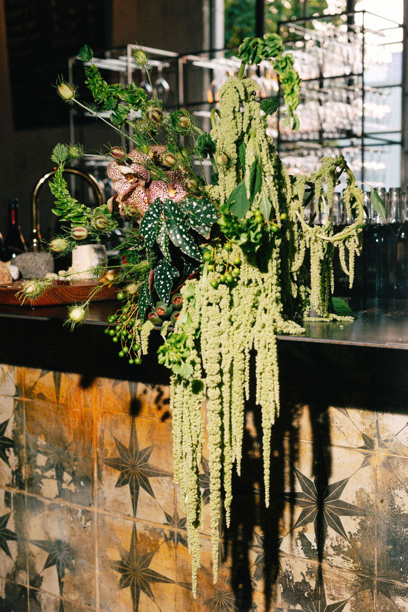 modern floral arrangement by kado flower studios featuring green flower pods, green amaranth, and bells of ireland