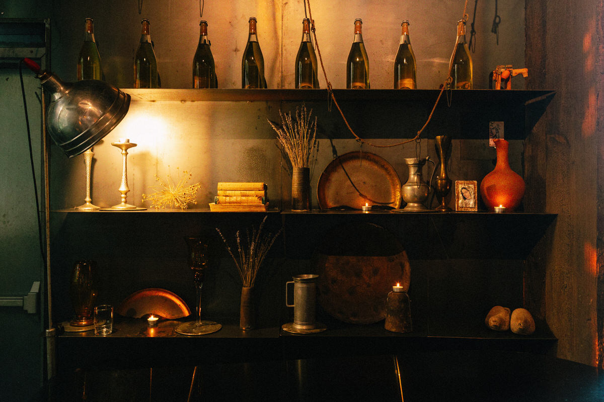 various wine bottles, vessels, and other found objects displayed on shelving inside la fabrique st george winery