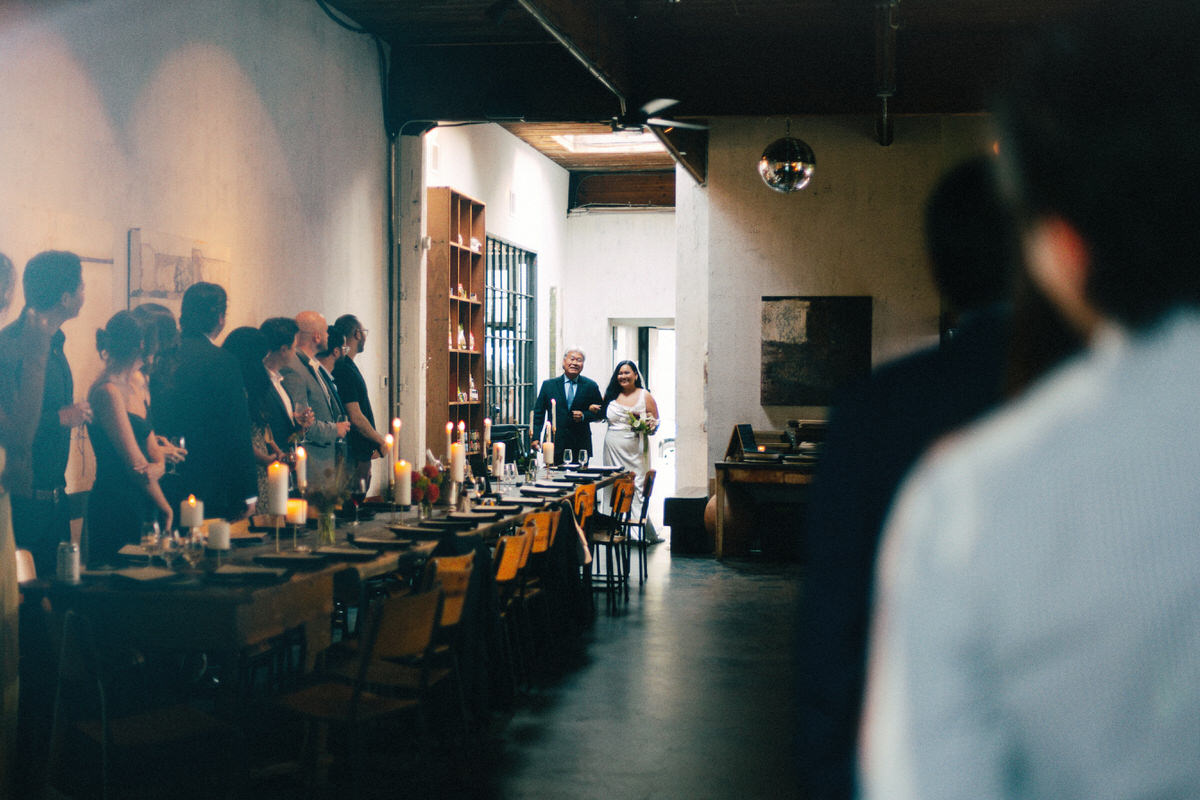 asian father walking into the event space at la fabrique st george with his wasian daughter on her wedding day