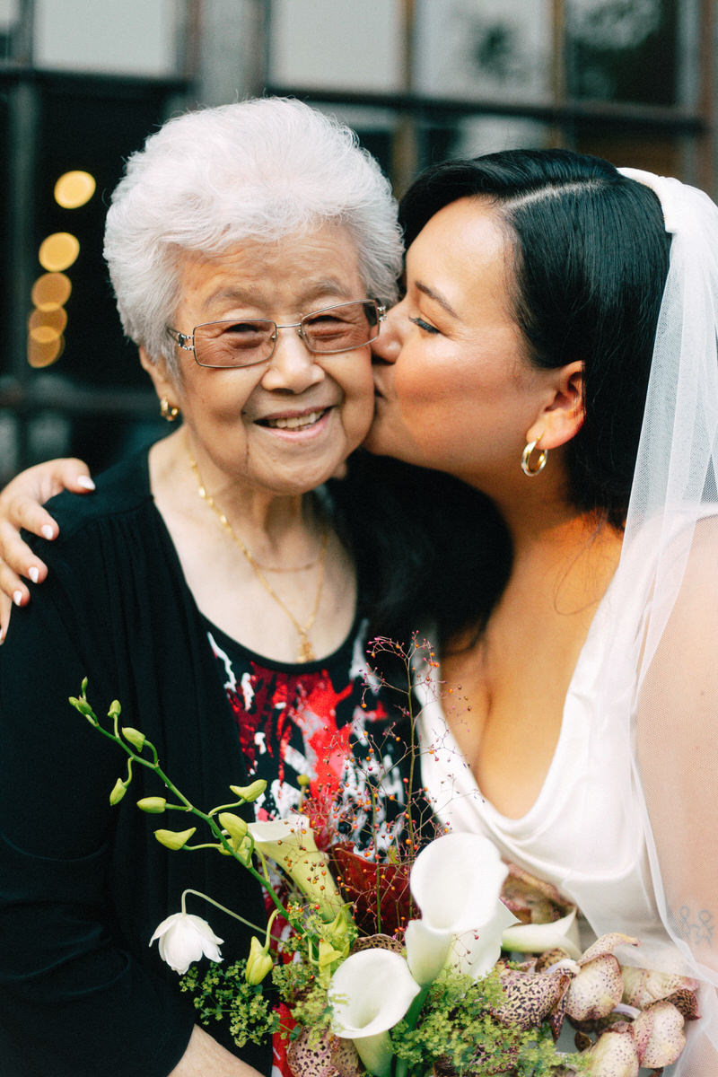 mixed race bride kissing her grandmother on the cheek