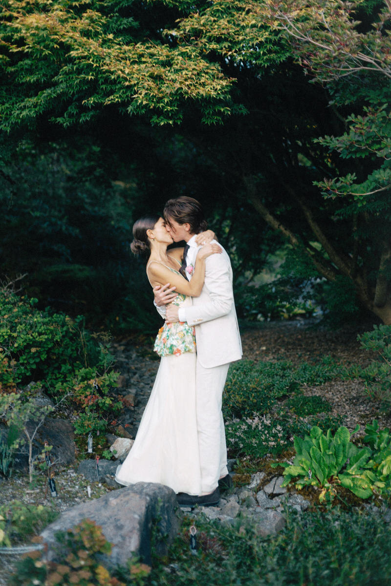bride in Markarian kissing her husband underneath a tree canopy at UBC Botanical Garden