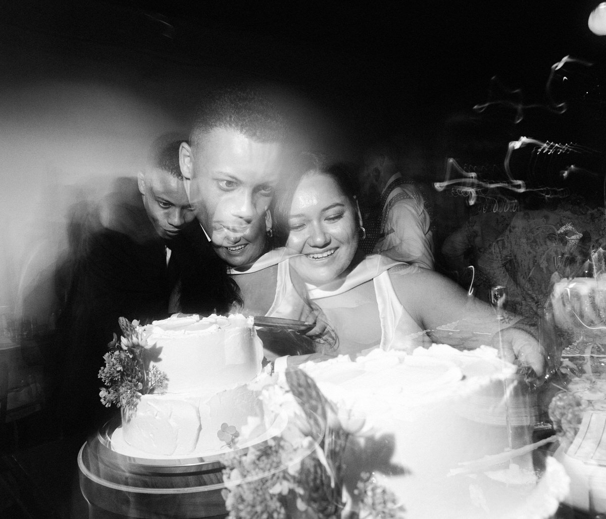 newlyweds cutting wedding cake inside la fabrique st george. multiple in camera exposures are used to convey energy and multiple moments in one image