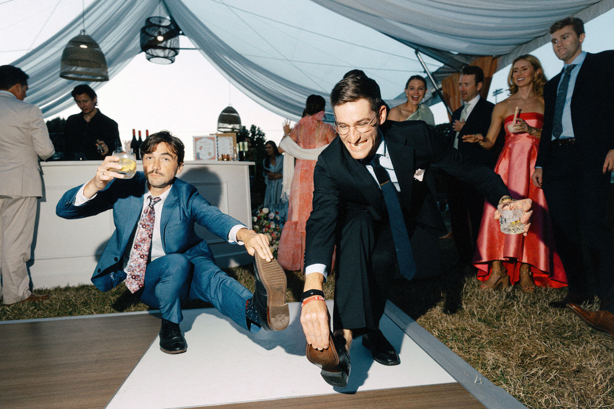 photojournalistic photo of wedding guests dancing while holding their shoes at the UBC Botanical Garden