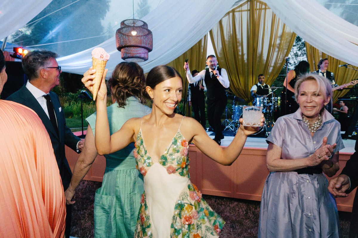 happy bride wearing Markarian Isabeau Gown while holding a drink and ice cream cone at her UBC Botanical Garden wedding